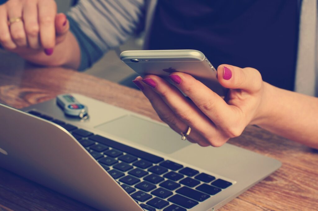 Person using a smartphone and laptop in an office